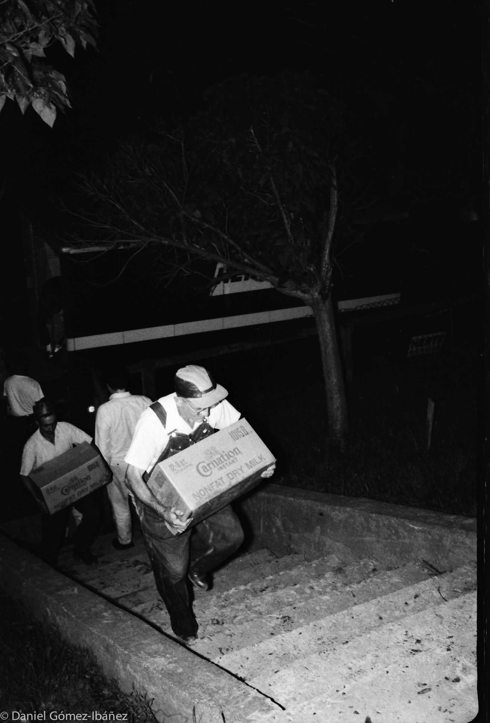Miners carry cases of dry milk into the hall.
